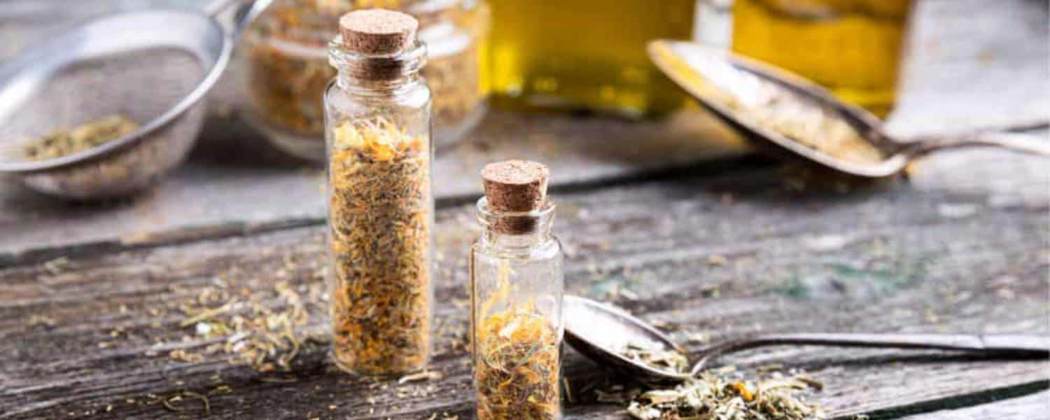 Bottles filled with herbs and natural oils on a wooden table – representing natural ingredients and their healing benefits.